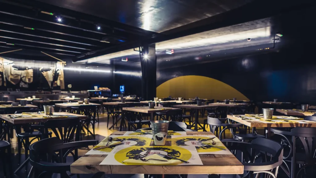 Pictured is the restaurant hall with wooden tables set with placemats.