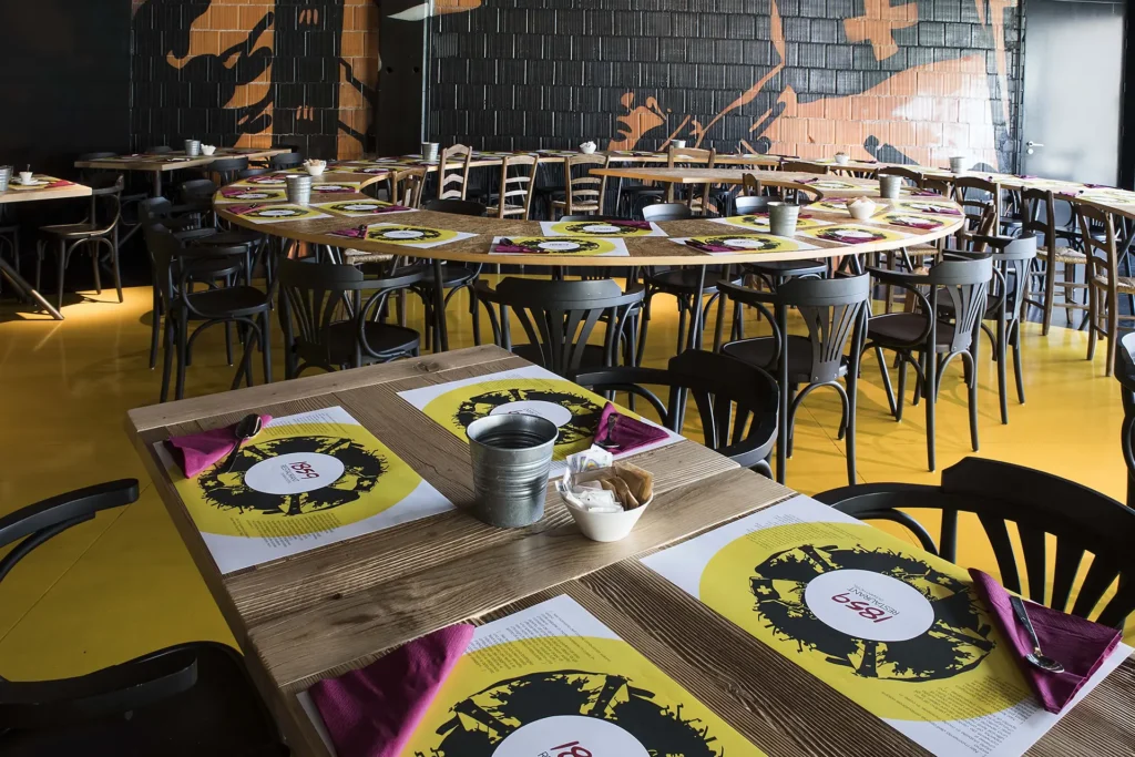 Pictured is the restaurant hall with wooden tables set with placemats
